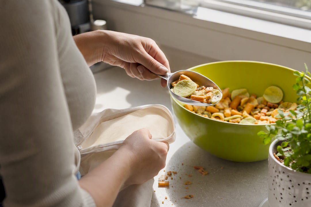 Hands pouring plant-based chips into a snack bag