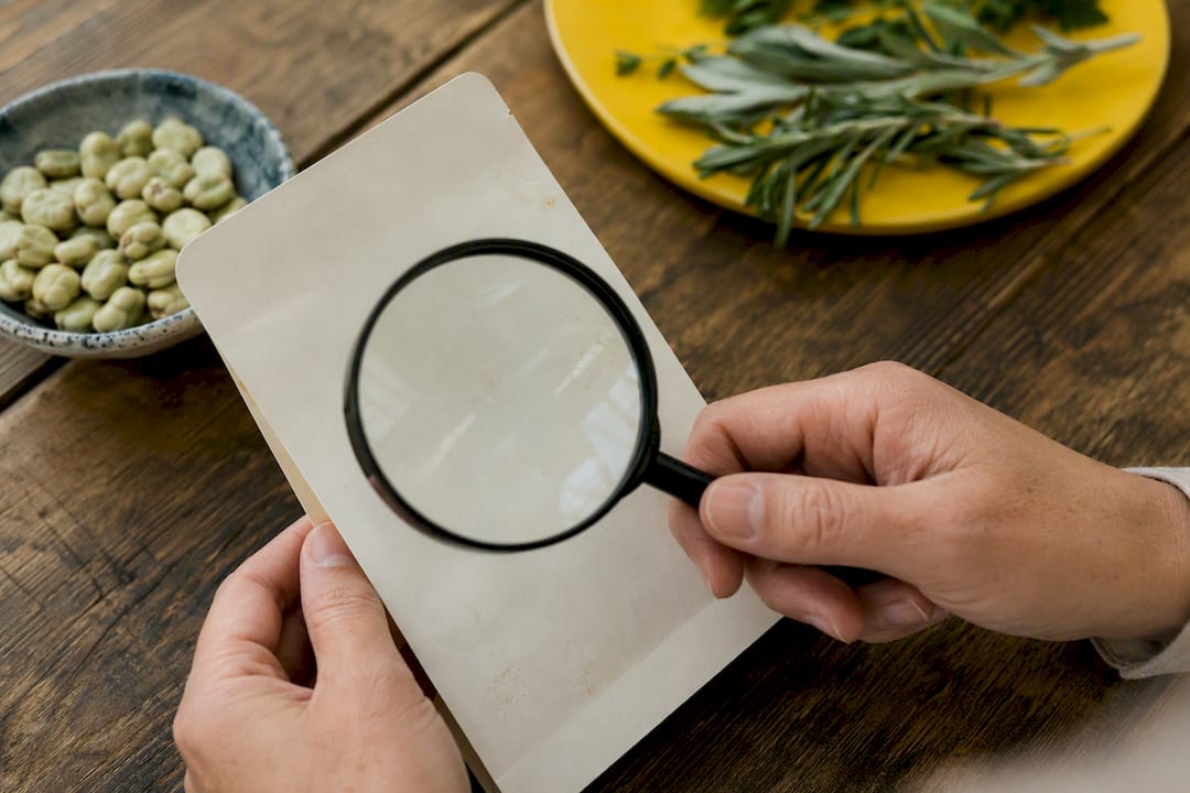 Hands examining ingredient label with magnifier