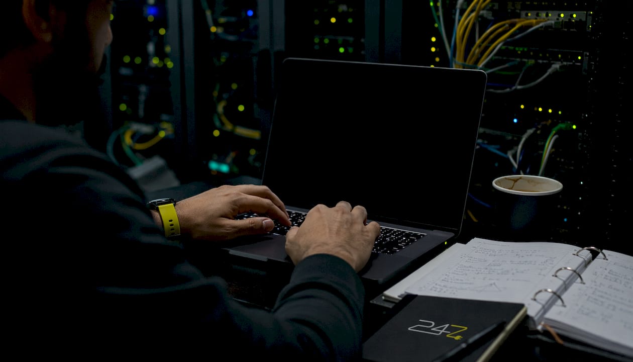 Hands typing laptop keyboard in server room