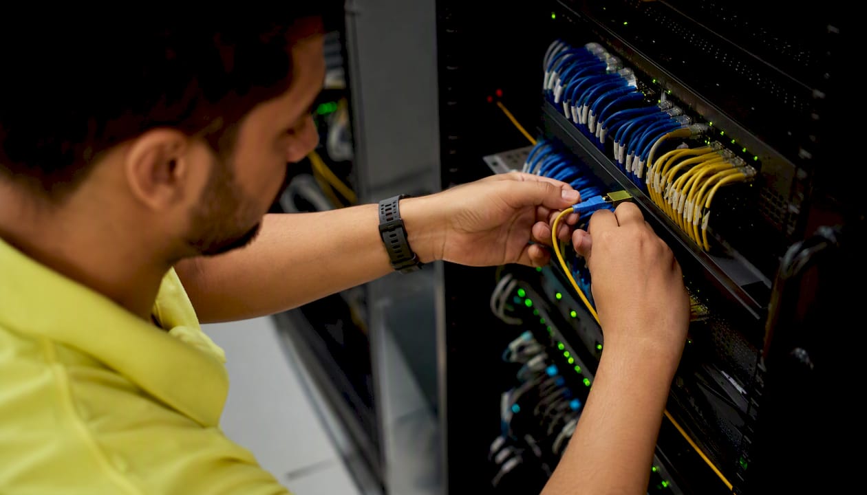 Hands connecting cables in secure server rack