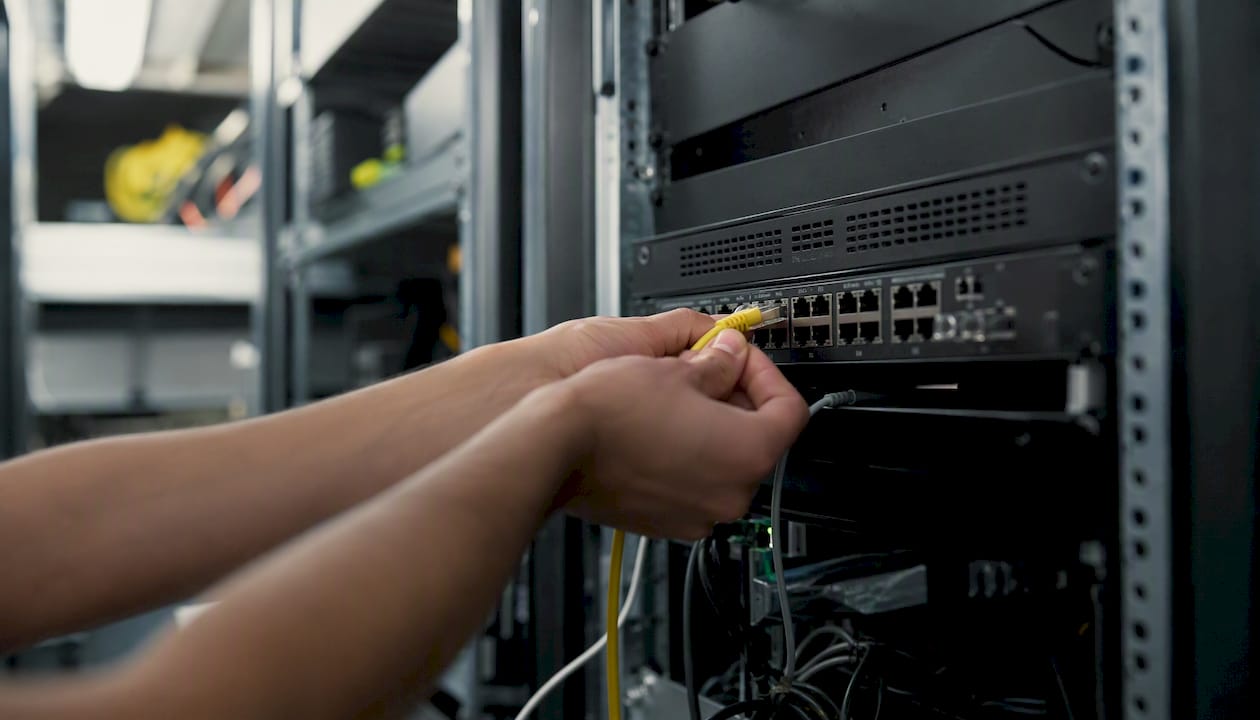 Hands plugging network cable into switch