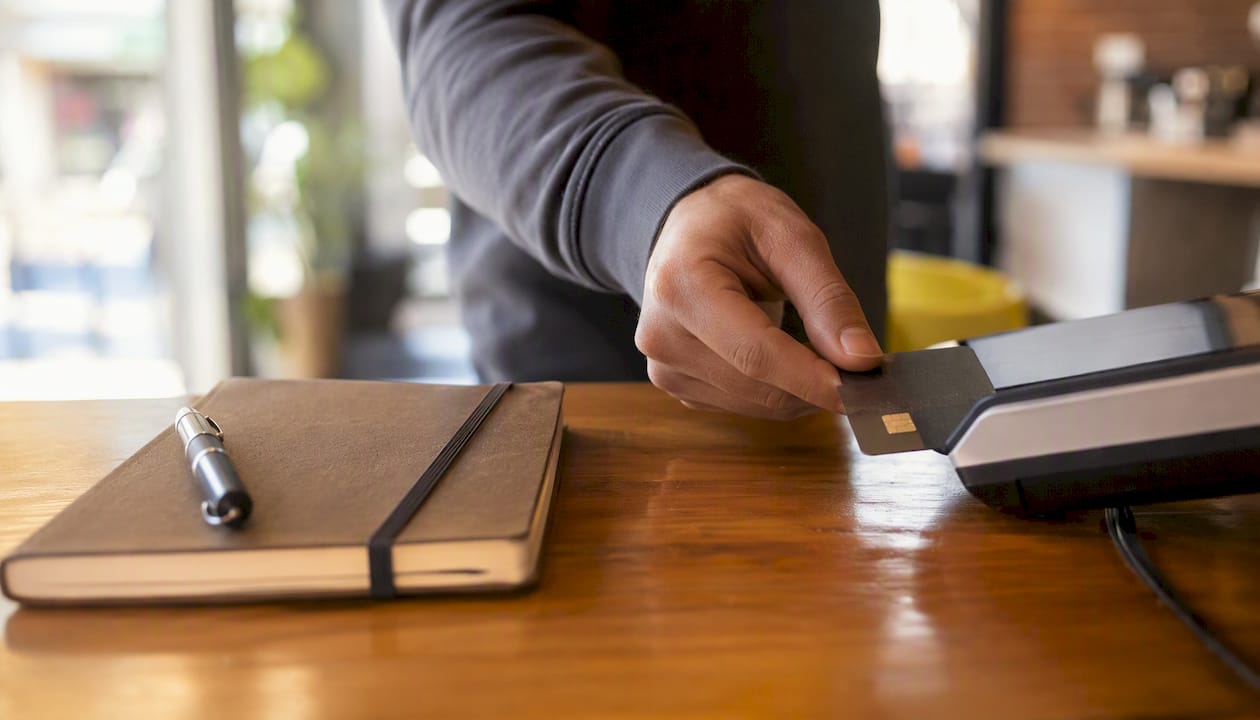 Hand holding payment card near POS terminal