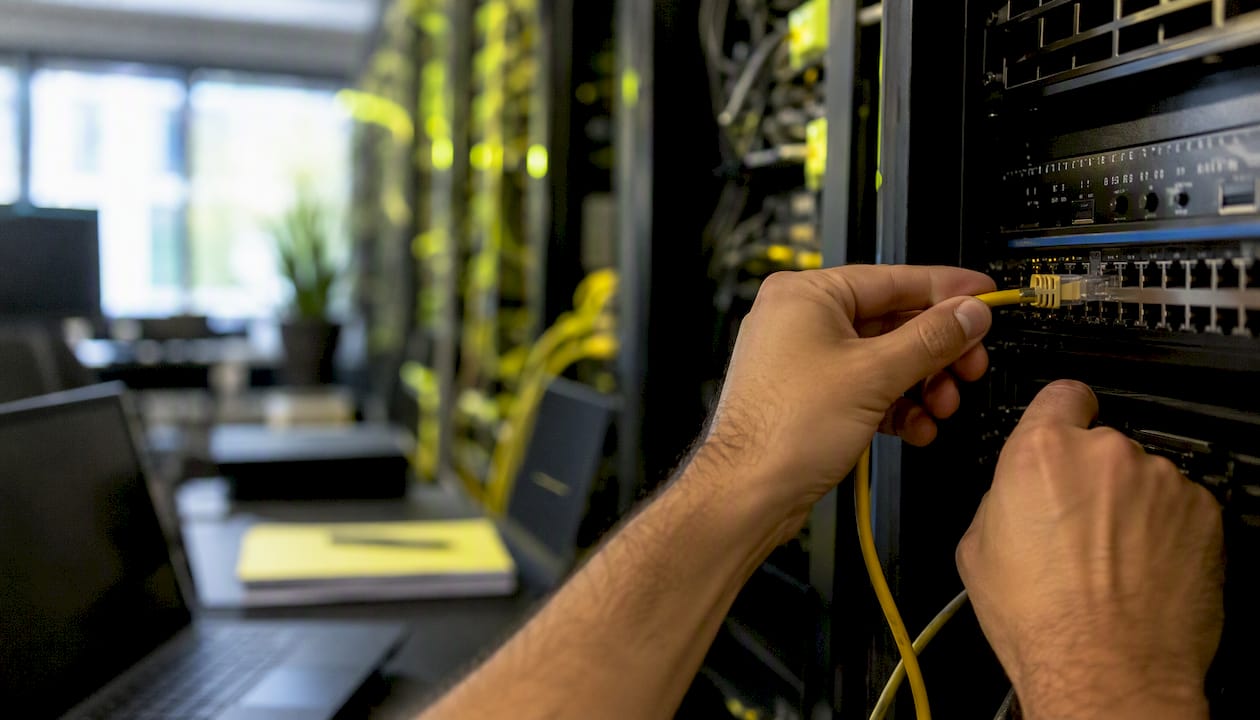 Hands securing network cable in startup server room