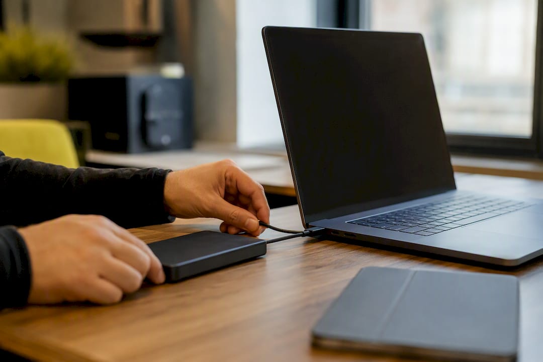 Hands connecting external drive to laptop
