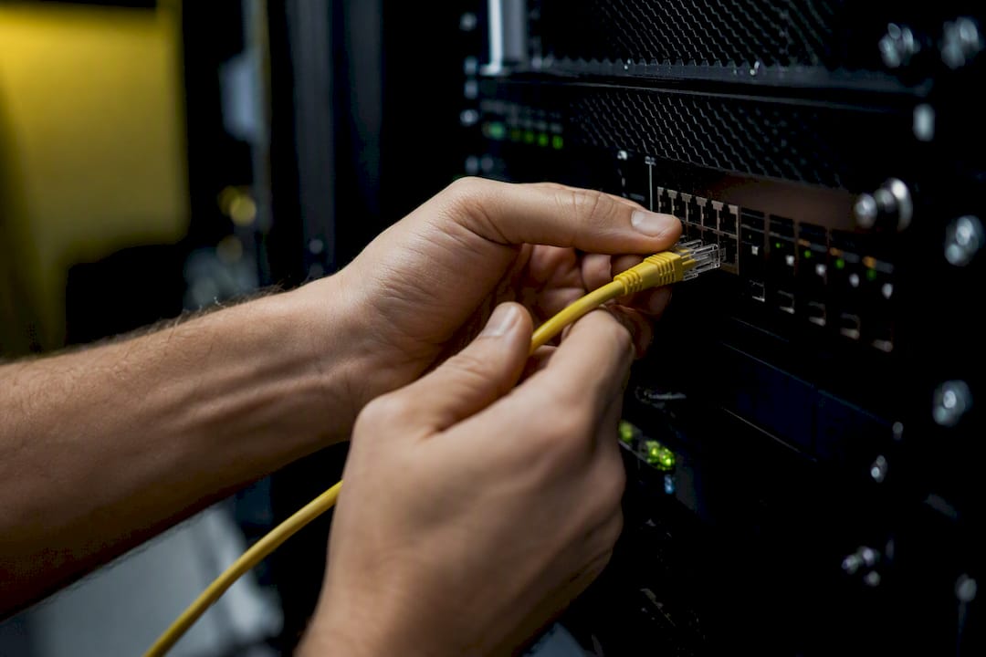 Hands connecting network cable in server room