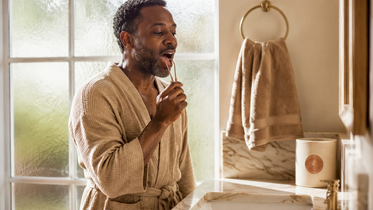 Man performing tongue scraping wellness ritual