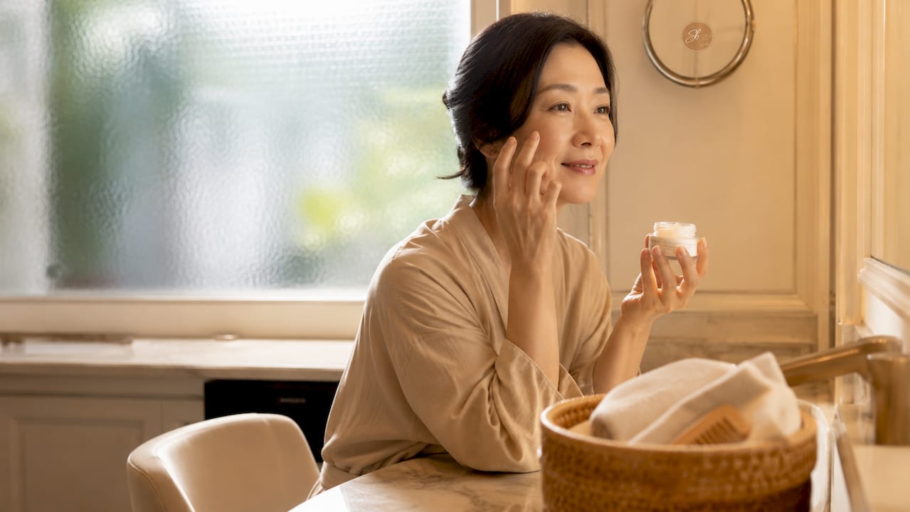 Woman scooping moisturizer for skin hydration