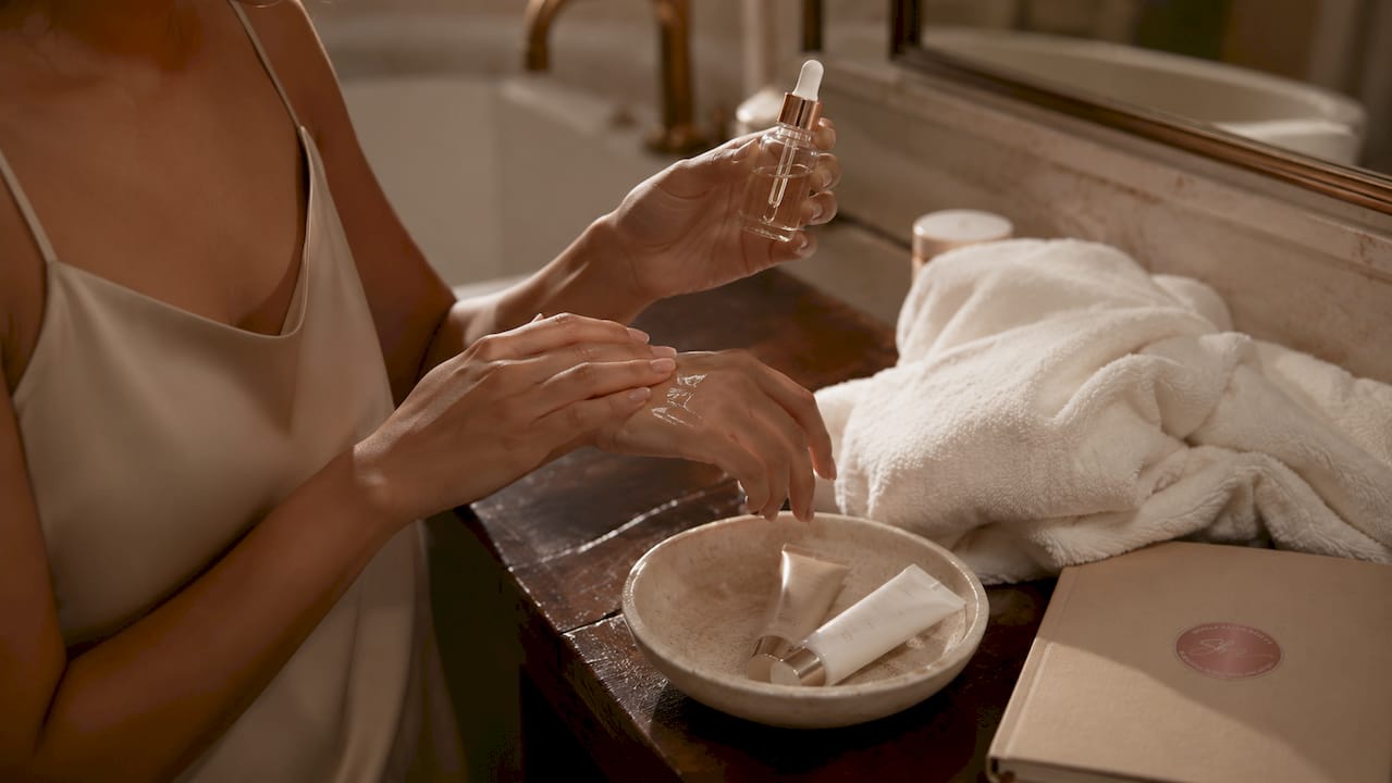 Hands applying exfoliating serum in bathroom