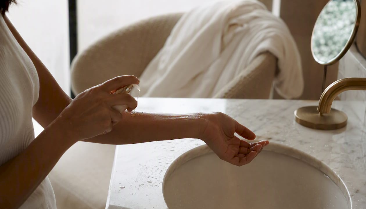 Hands applying serum to damp skin in luxury bathroom