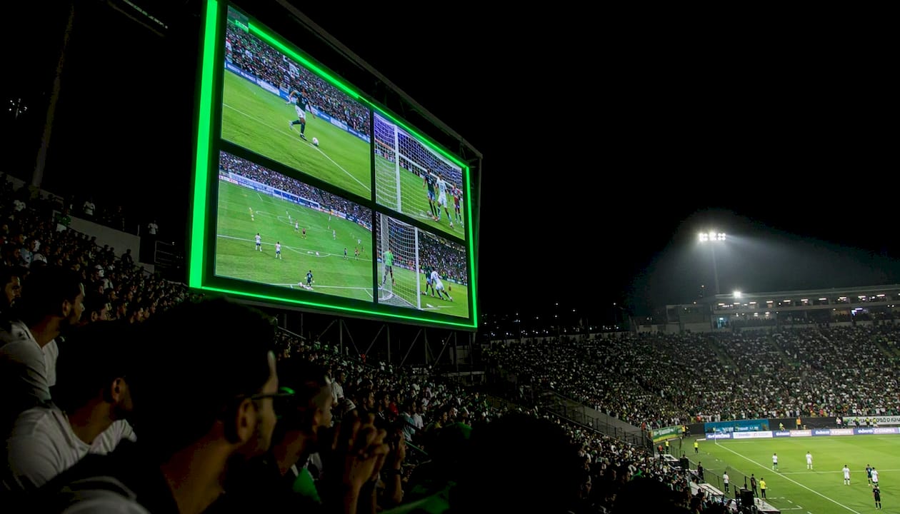 Stadium scoreboard showing fast soccer highlight clips