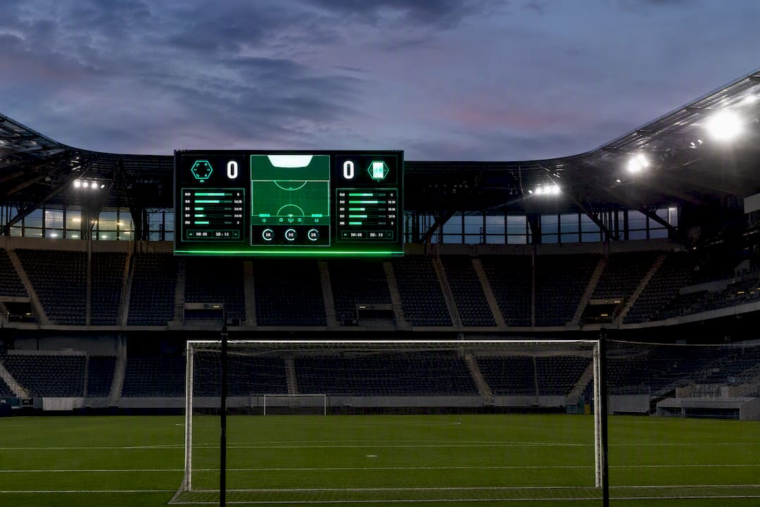 Football stadium digital scoreboard at dusk