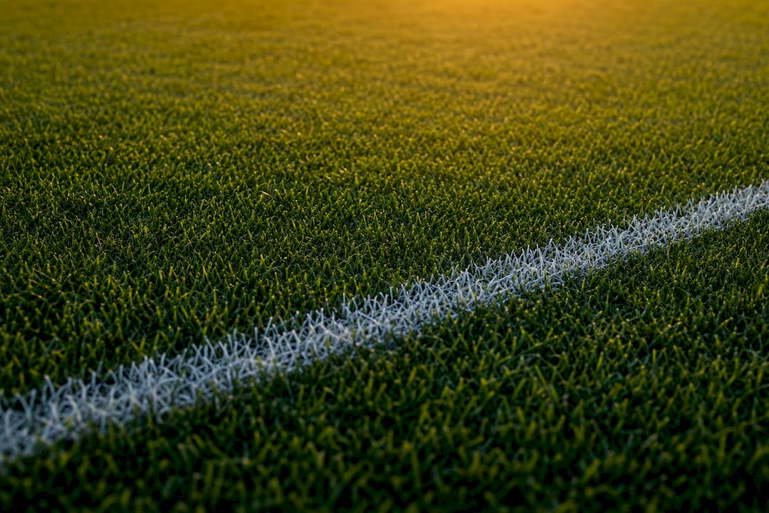 Close-up of pristine football pitch grass and white line