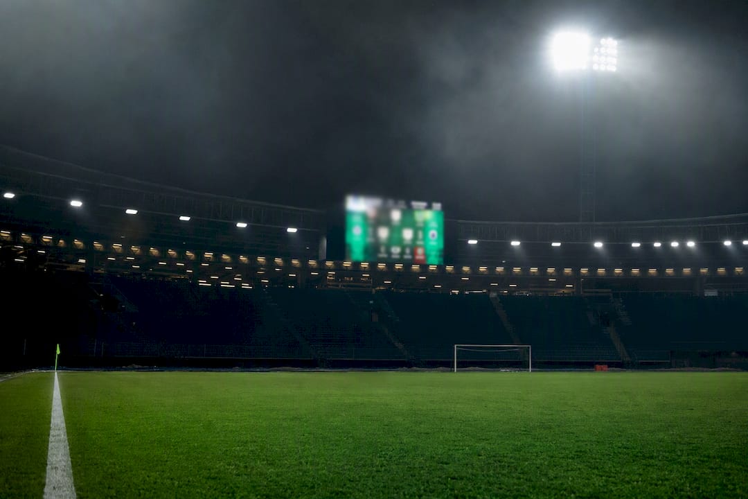 Football stadium with illuminated scoreboard at night
