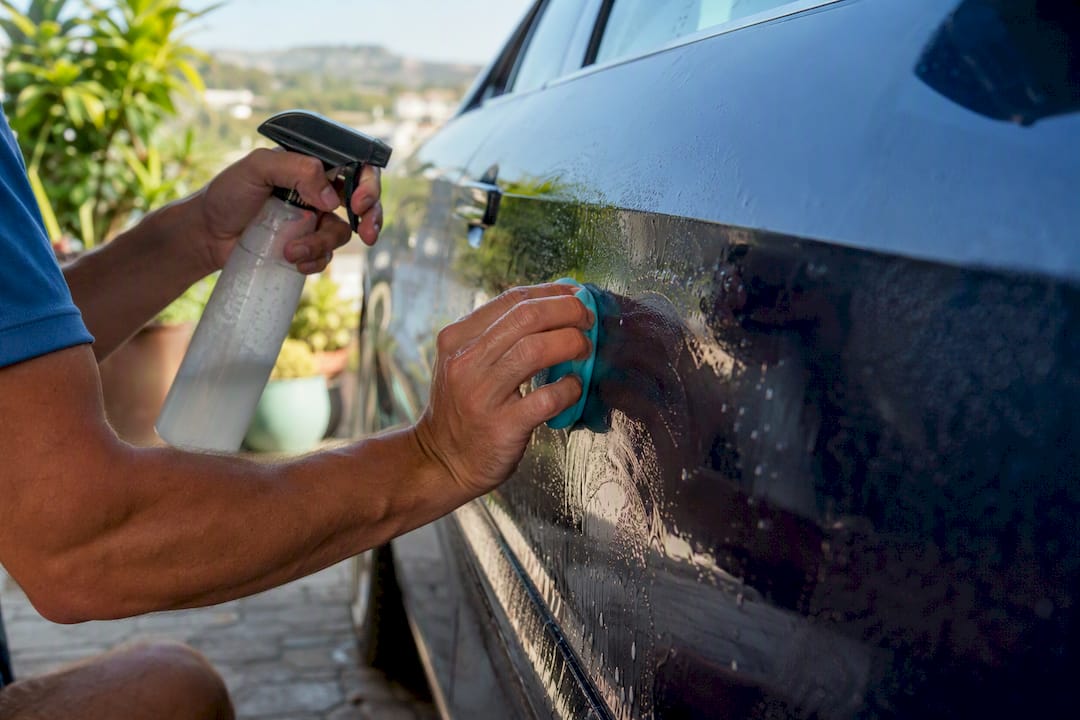 Hands clay bar decontaminating car paint surface