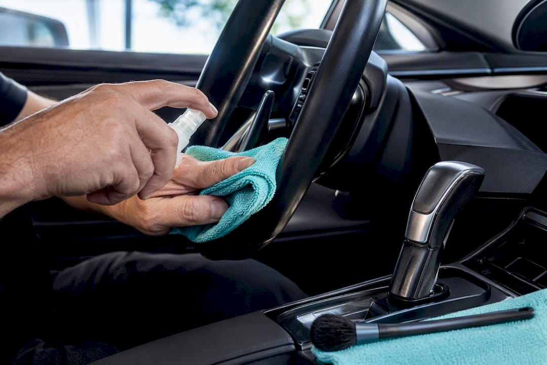Hands cleaning steering wheel and shifter