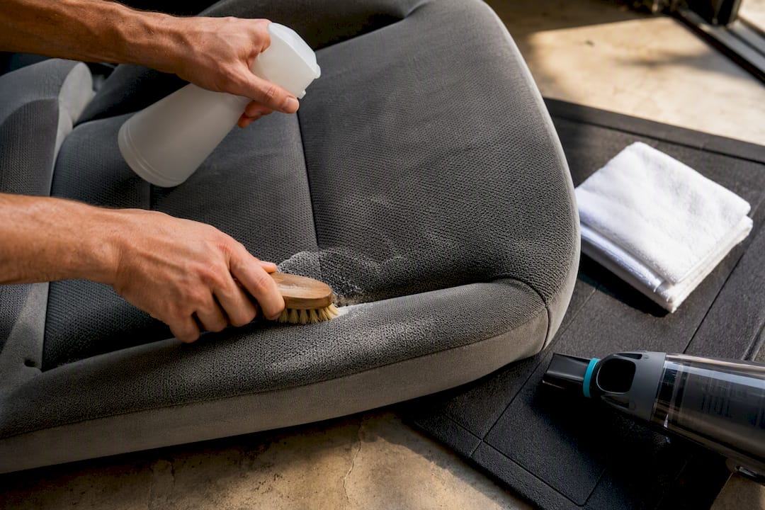 Hands spot-cleaning vehicle seat upholstery