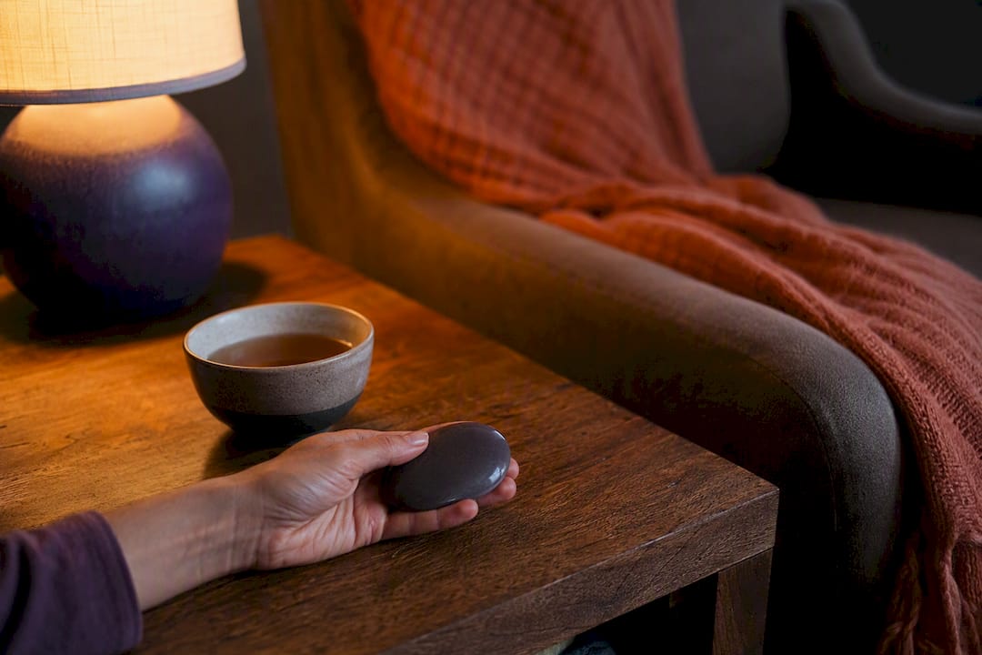 Hand holding worry stone on table with calming objects