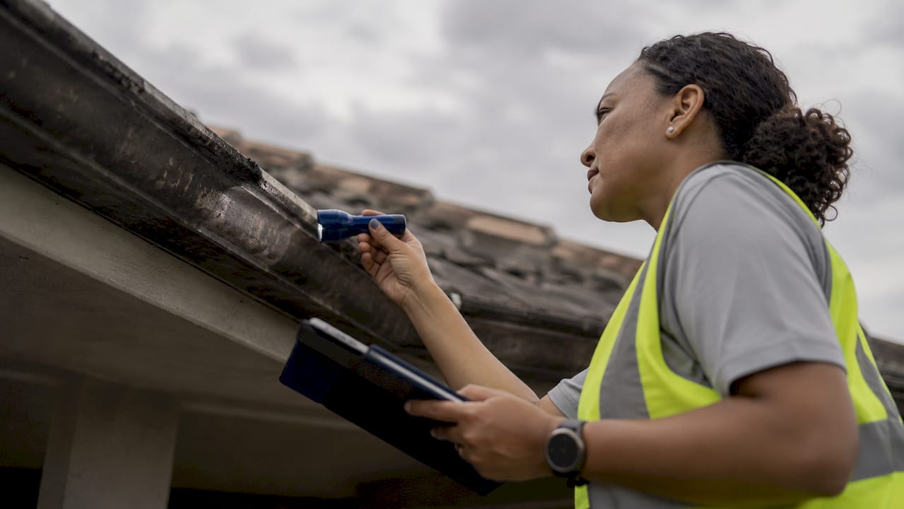 Maintenance worker inspecting retirement village roof gutter