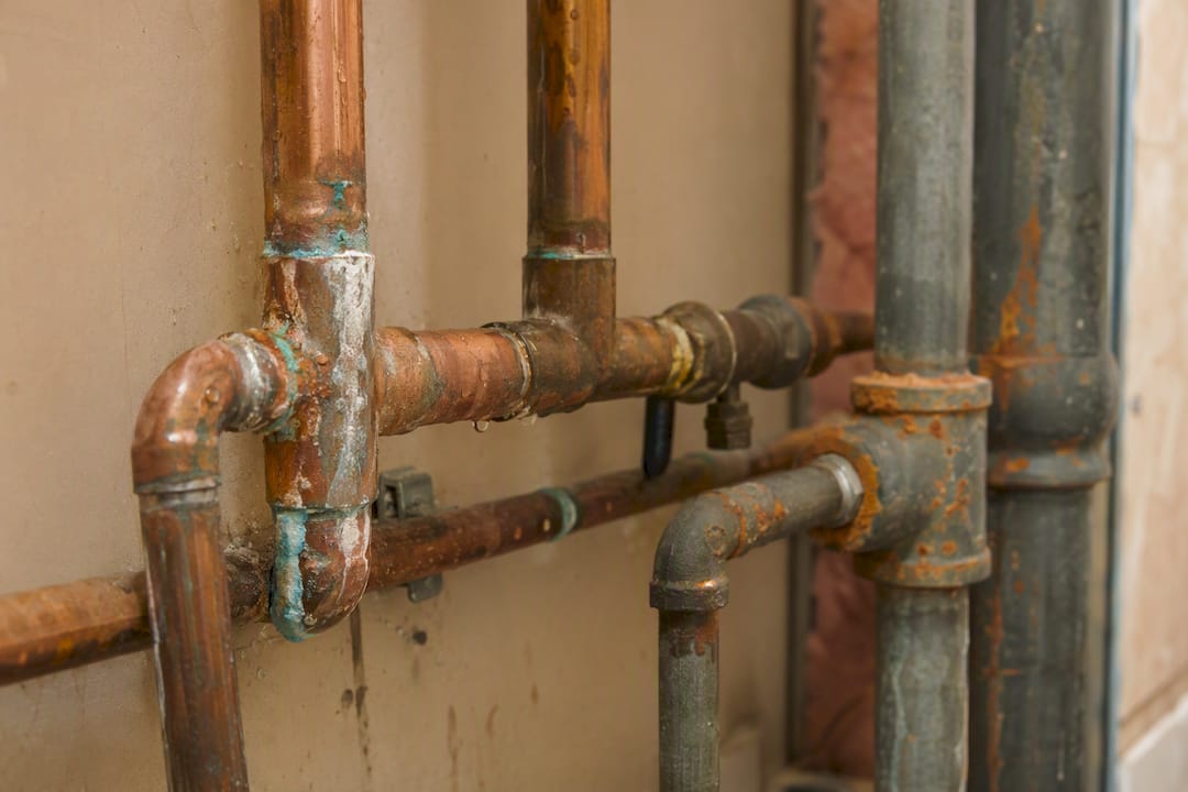 Close-up of corroded copper and rusty galvanized pipes