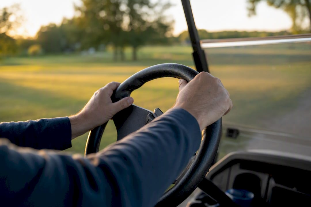 Hands tightly gripping golf cart steering wheel
