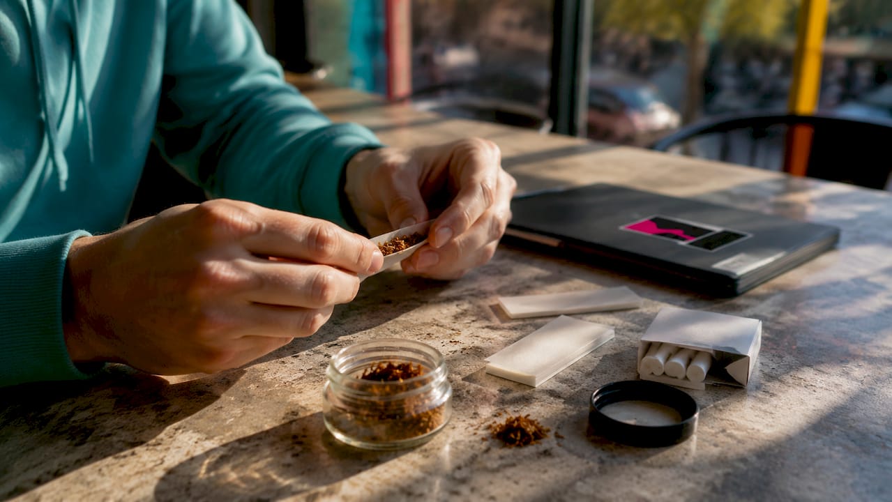 Hands hand-rolling cigarette with tobacco