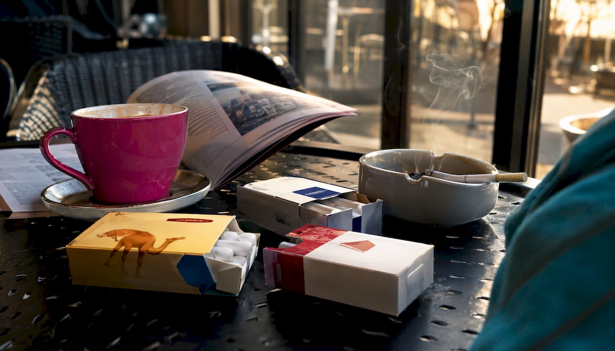 Cigarette packs with coffee and smoke on wood table