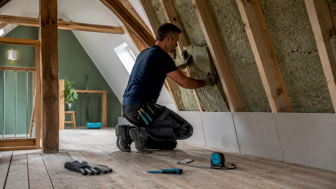 Detailopname van handen die isolatiemateriaal aanbrengen in een huis