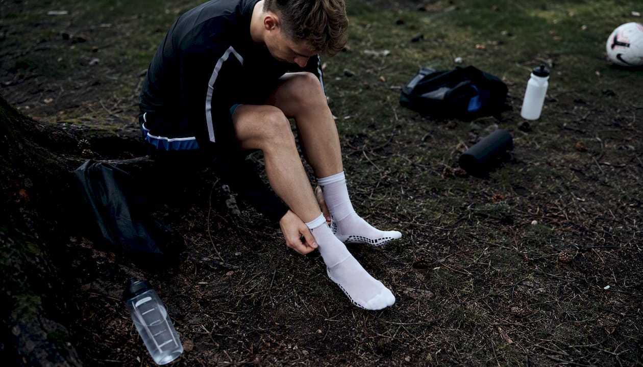 Ein Fußballerfuß mit rutschfesten Socken und hochgezogenen Stutzen auf dem Platz.