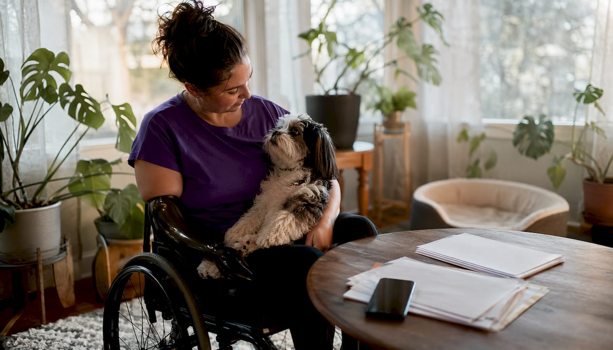 Disabled woman with her dog in wheelchair at home