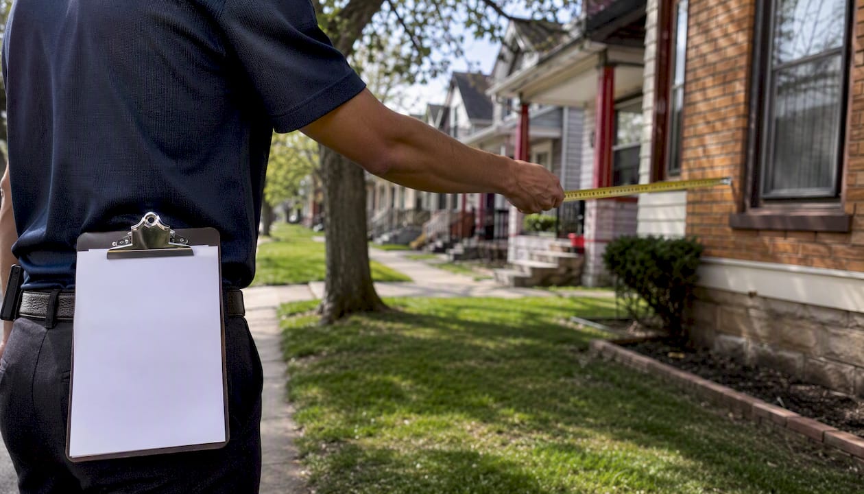 Appraiser measuring house exterior in Detroit