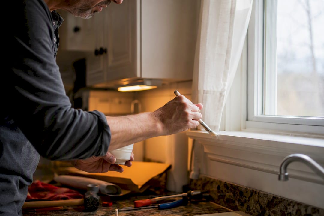 Hands painting door frame during home prep