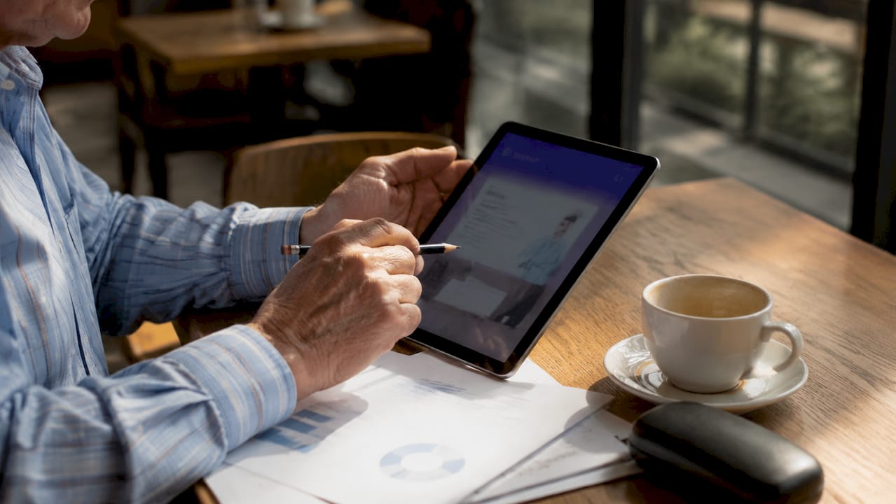 Una persona consulta un tablet en la biblioteca para recibir apoyo educativo con inteligencia artificial.