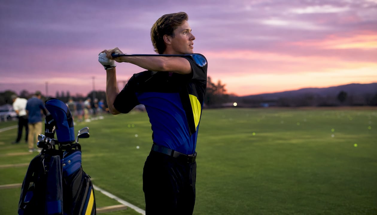 Golfer in avant-garde apparel taking backswing outdoors
