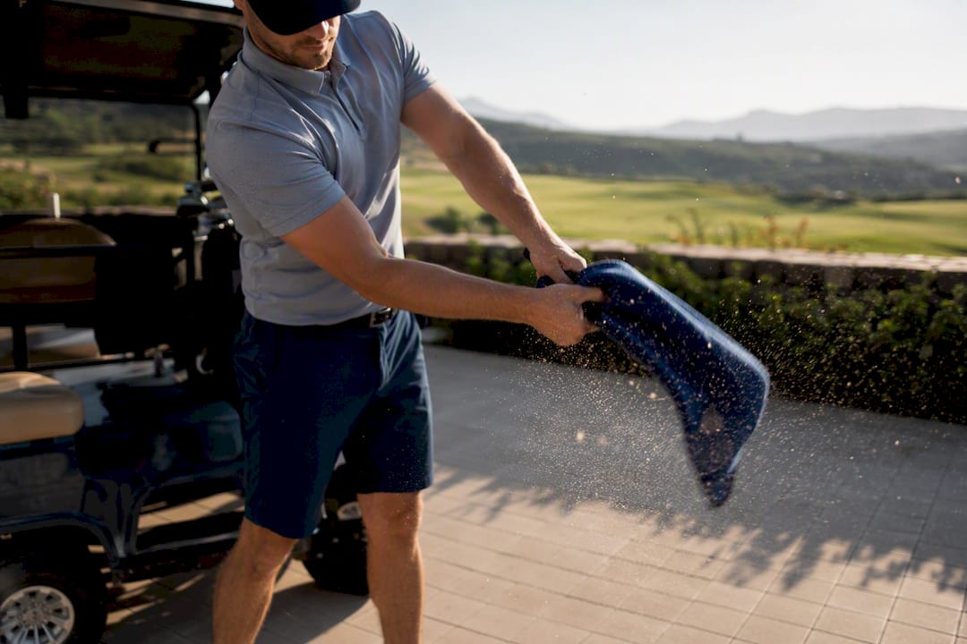 Golfer shaking grit out of golf headcover outdoors