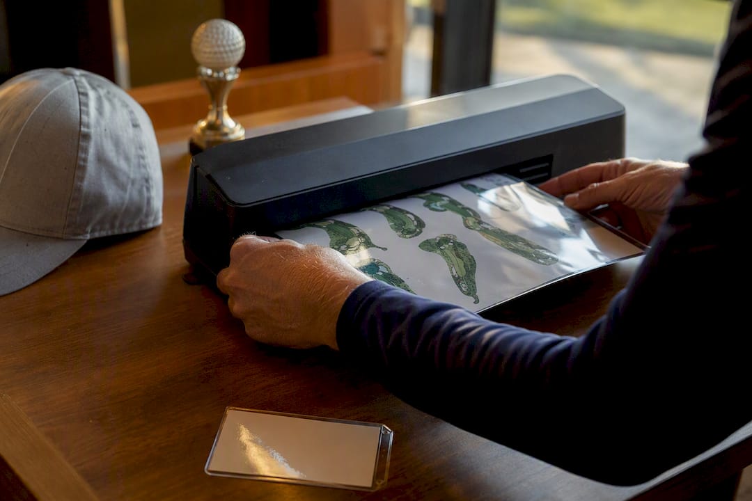 Golfer laminating yardage book pages