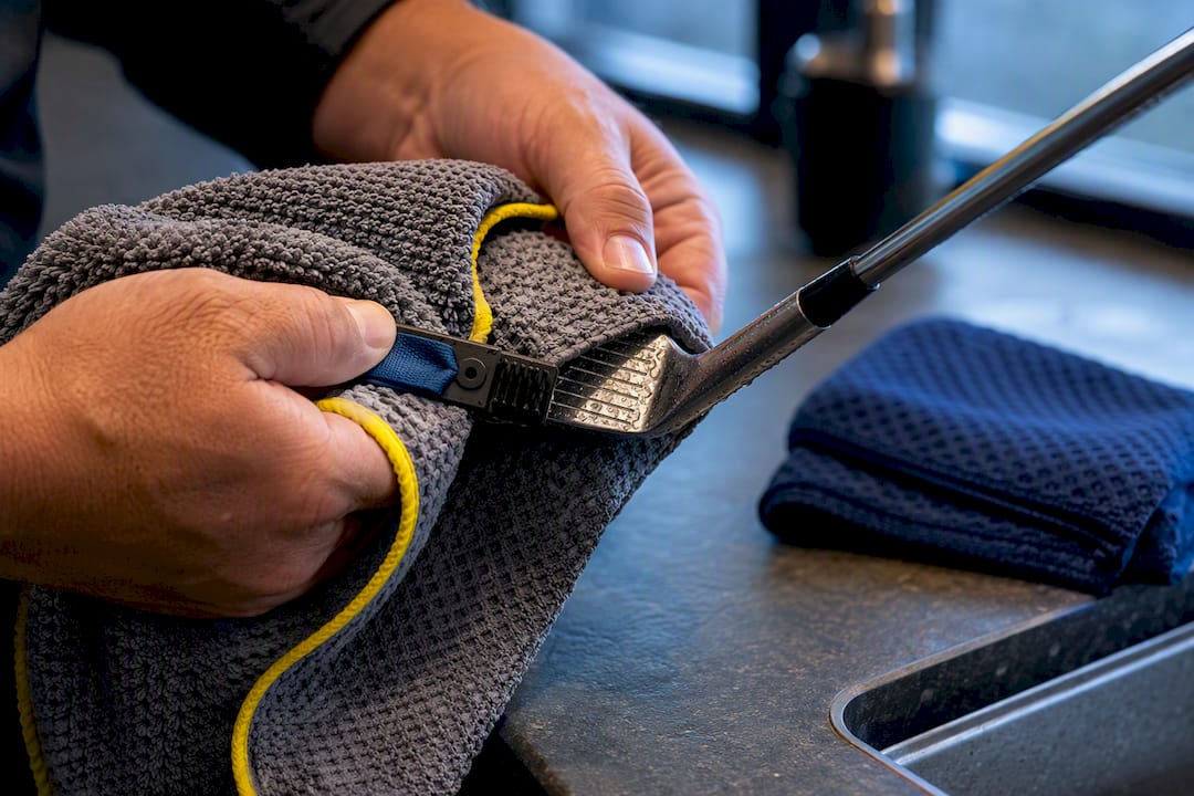 Hands cleaning club grooves with towel
