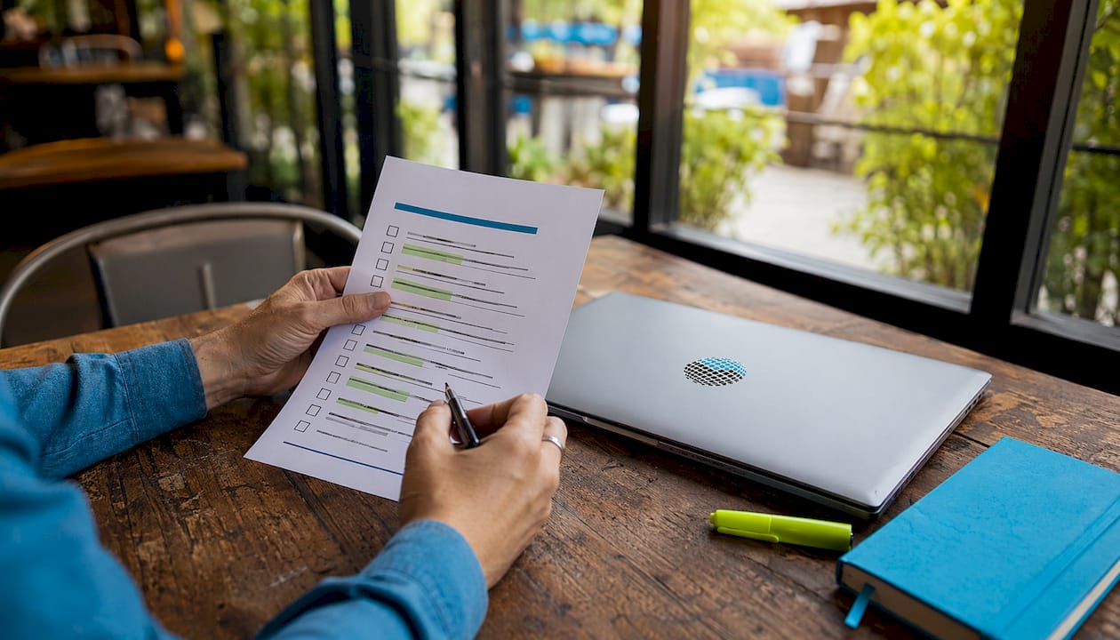Hands holding SEO audit checklist on white desk