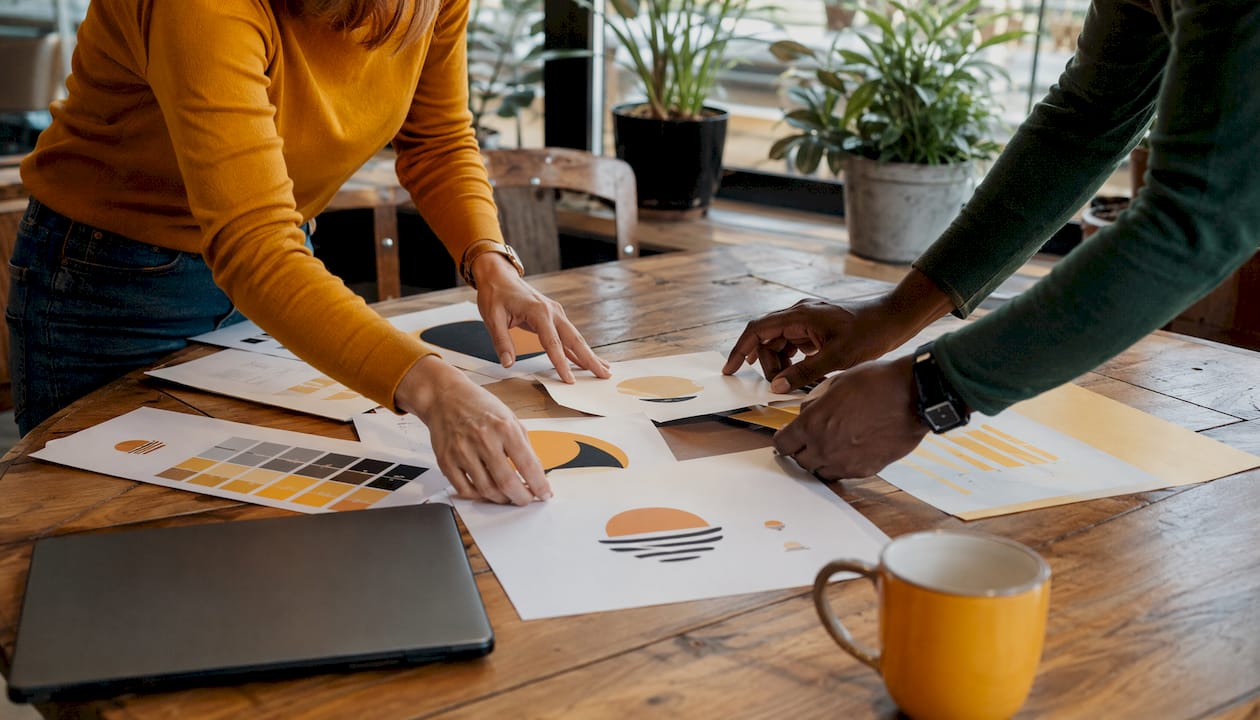 Hands sorting printed brand assets for migration