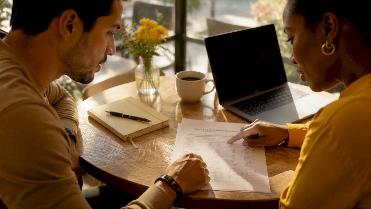 Hands discussing whole life insurance policy documents overhead