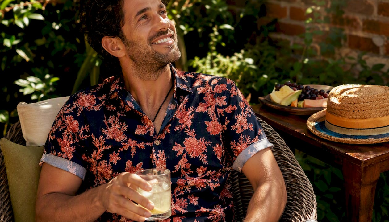 Man in Dan Flashes forest green Hawaiian shirt at patio