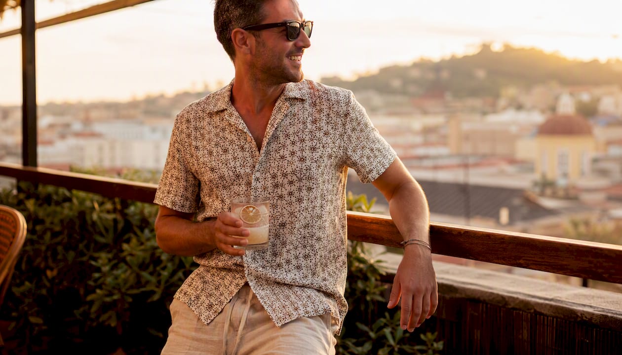 Man in patterned camp shirt at rooftop bar