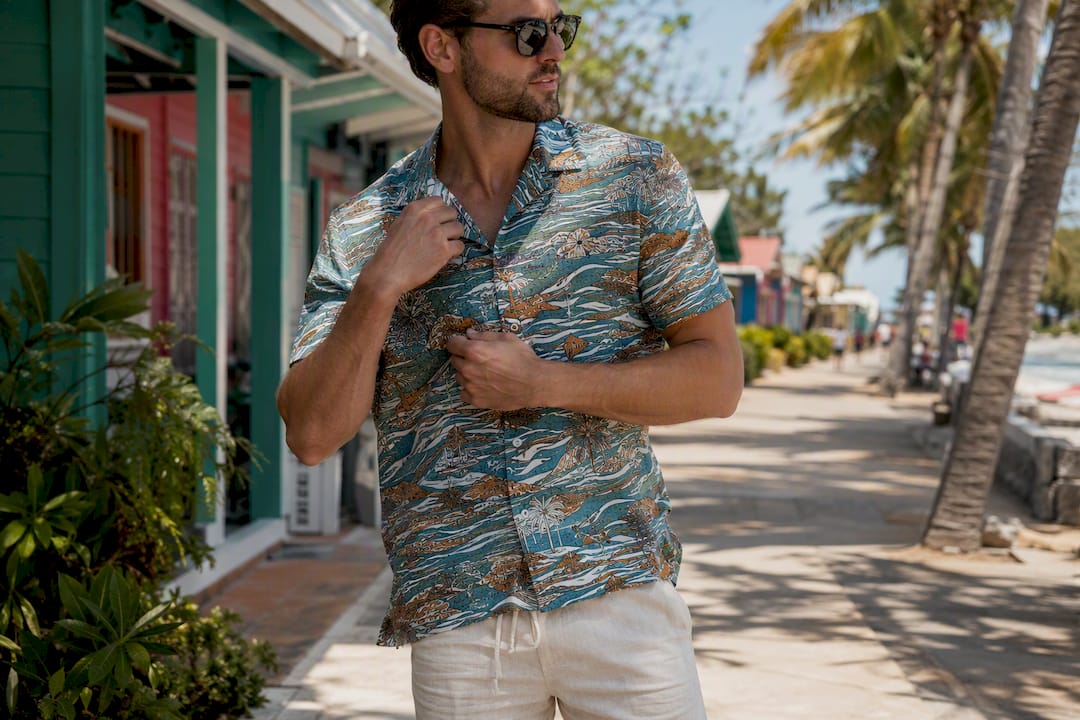 Man adjusting collar of colorful camp shirt outdoors