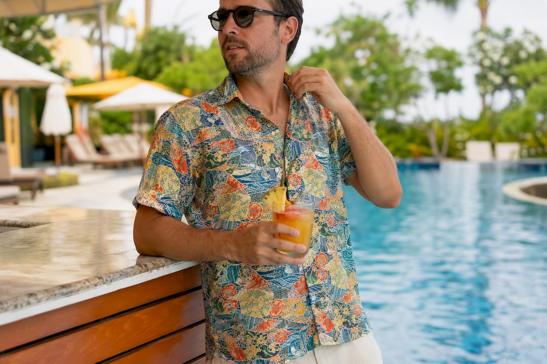 Man adjusting collar wearing bold vacation Hawaiian shirt