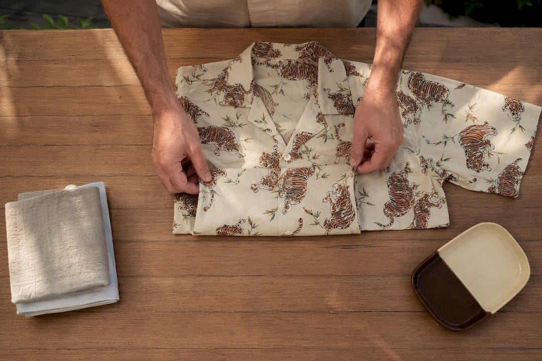 Hands folding a verified patterned beach shirt