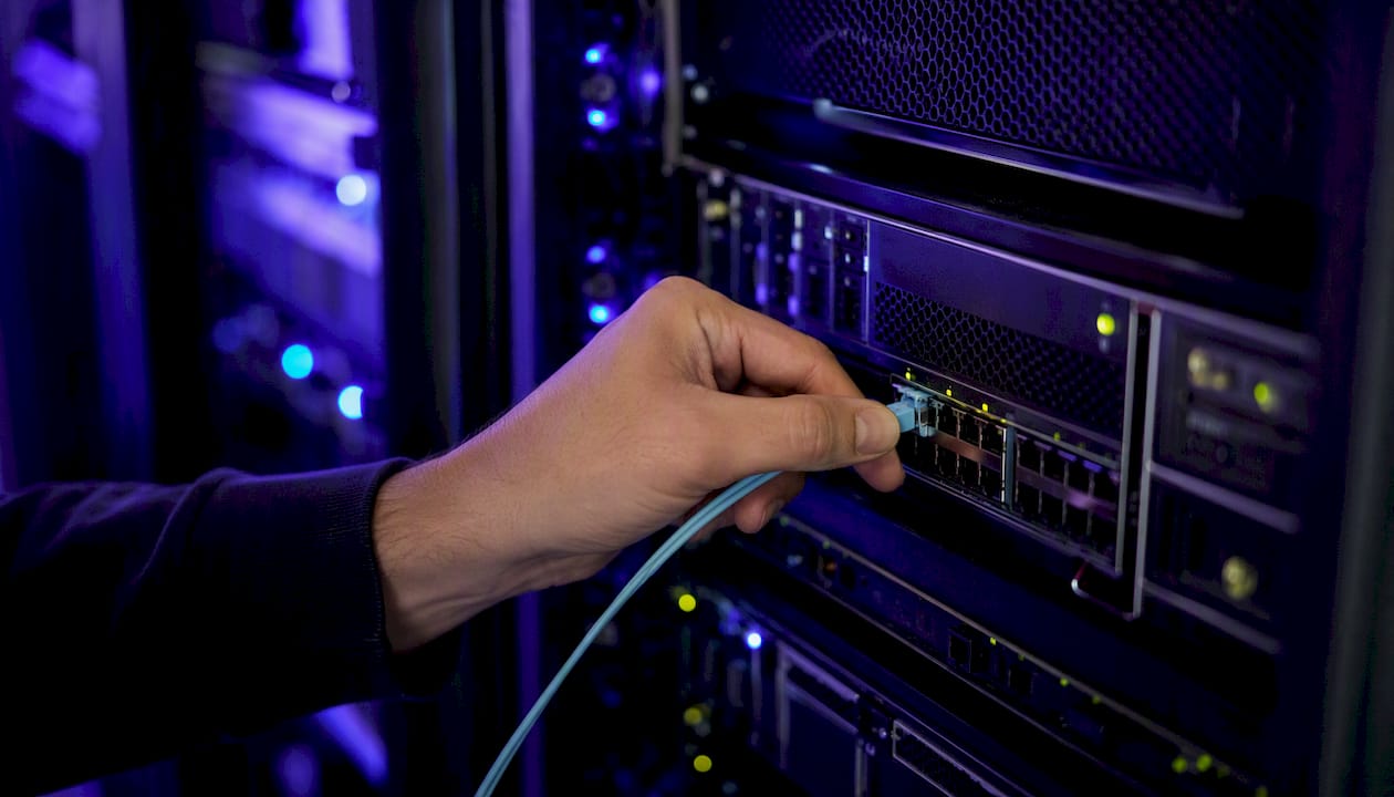 Hand connecting fiber optic cable in data center