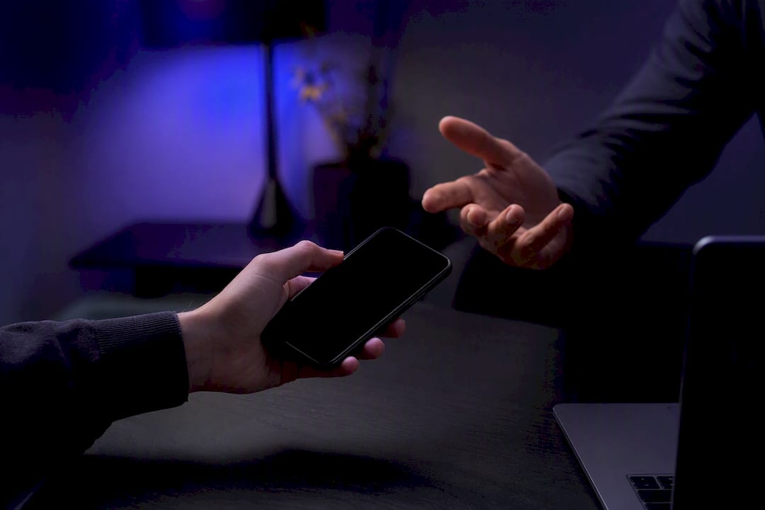 Hand holding phone with screen off in dim light