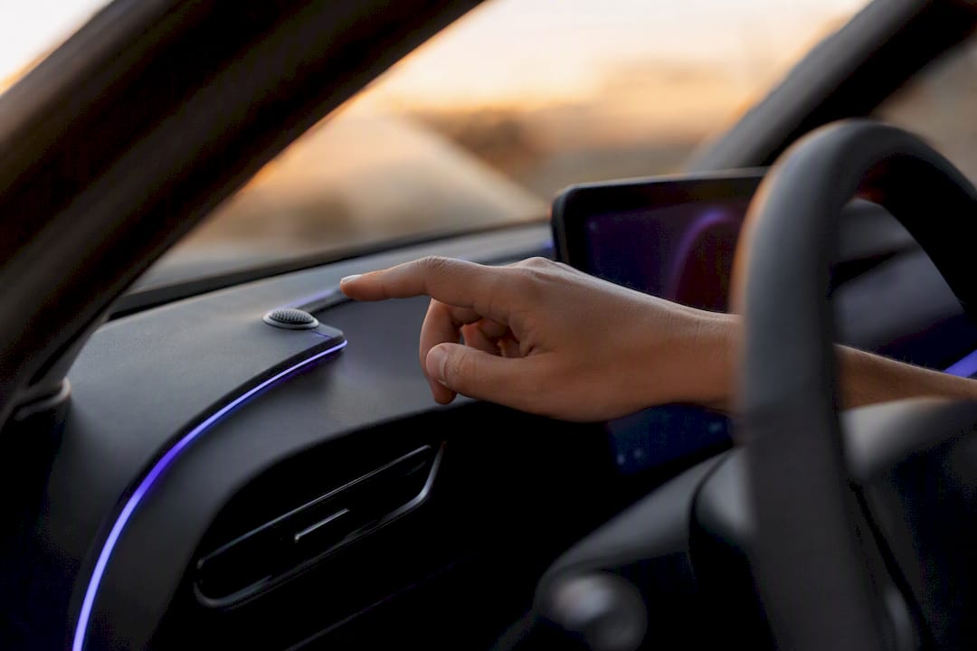 Hand near car dashboard microphone for voice command