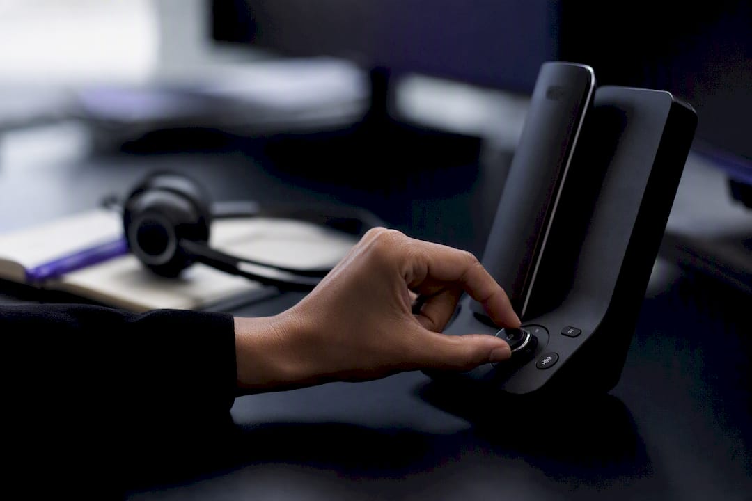 Hand pressing mute on desk phone