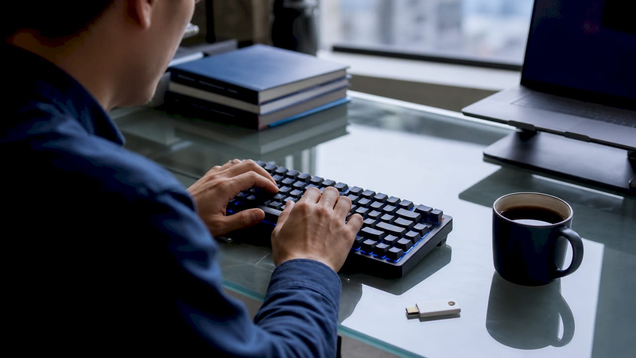 Hands typing password with hardware security key nearby