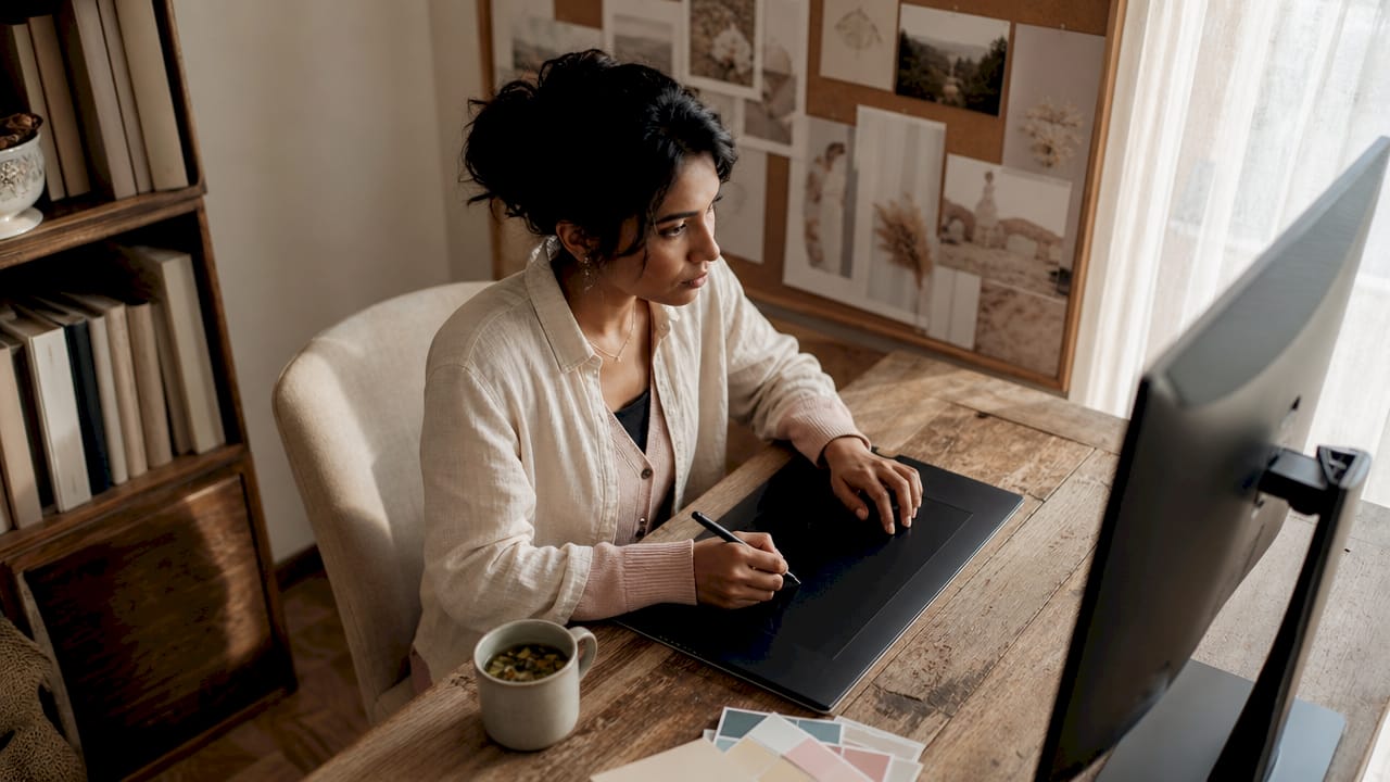 Woman editing wedding photos at desk in bright studio